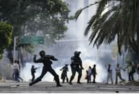 Cтолкновения между полицией и протестующими в Венесуэле. Полицейский бросает газовый баллончик в протестующих