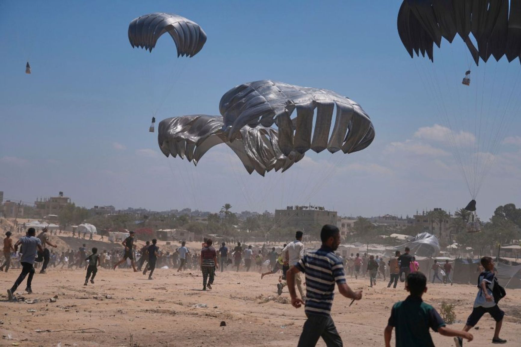 Palestinians chase parachuted aid in the city of Az-Zawaida, central part of the Gaza Strip – August 4, 2025 